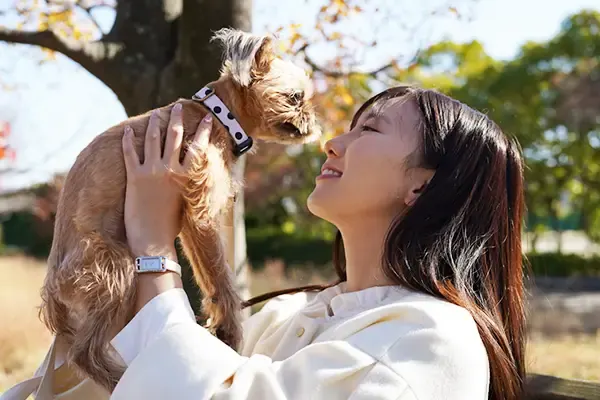 小さな犬を抱き上げて笑う女性