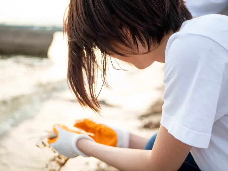 手袋をして浜辺で作業する人の手元